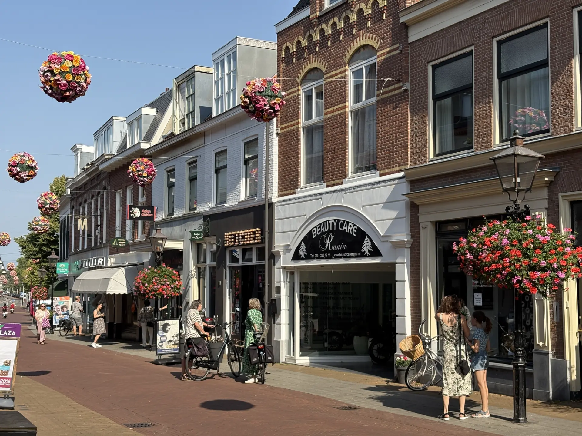 De Herenstraat in Rijswijk met historische panden, hangende bloembollen en voorbijgangers